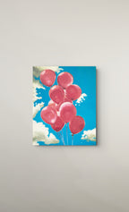 A square canvas wall art print depicting a cluster of pink balloons floating against a bright blue sky with white clouds, shown hanging on a light gray wall.